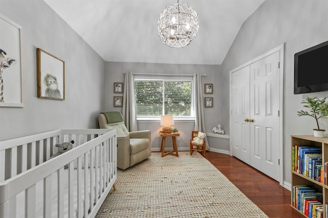 bedroom featuring lofted ceiling, a closet, an inviting chandelier, wood finished floors, and a crib