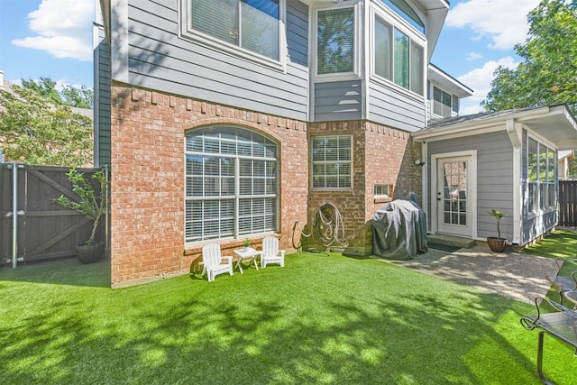 back of house with fence, brick siding, and a lawn