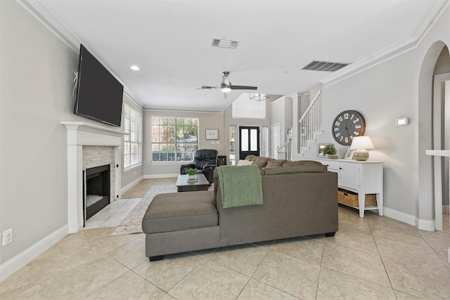 living area featuring ceiling fan, ornamental molding, a fireplace, and visible vents