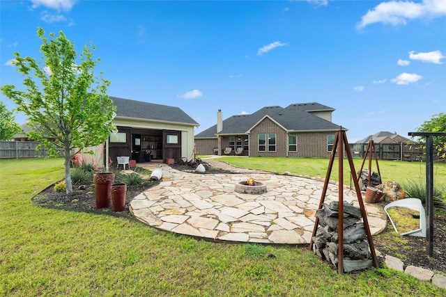 back of property with an outdoor fire pit, fence, a patio area, and a lawn