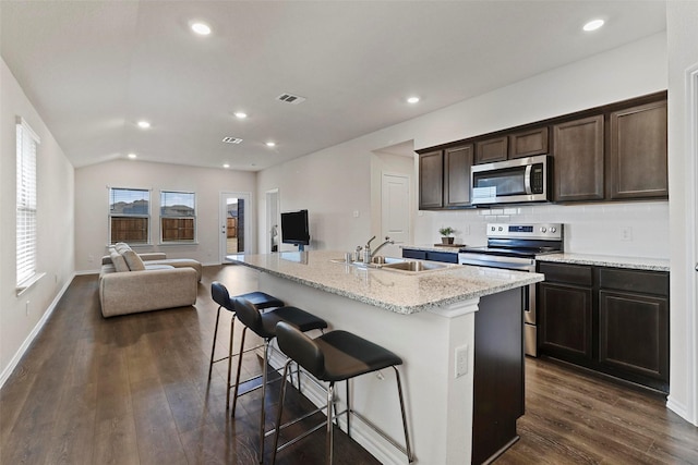 1628 Seadrift Dr, Forney, TX 75126 - kitchen with appliances with stainless steel finishes, open floor plan, dark wood-type flooring, dark brown cabinets, and a kitchen island with sink