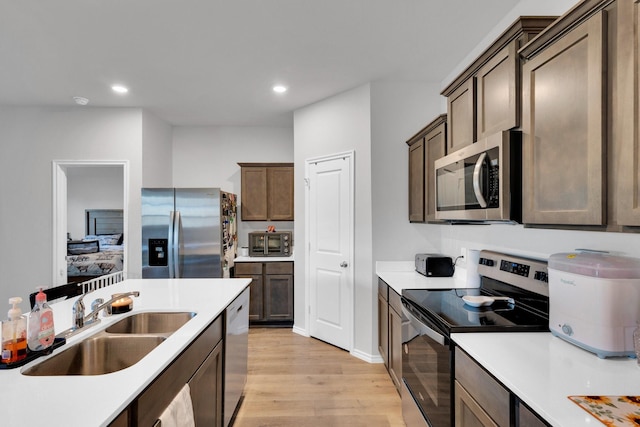 kitchen featuring a sink, appliances with stainless steel finishes, light countertops, light wood-style floors, and recessed lighting