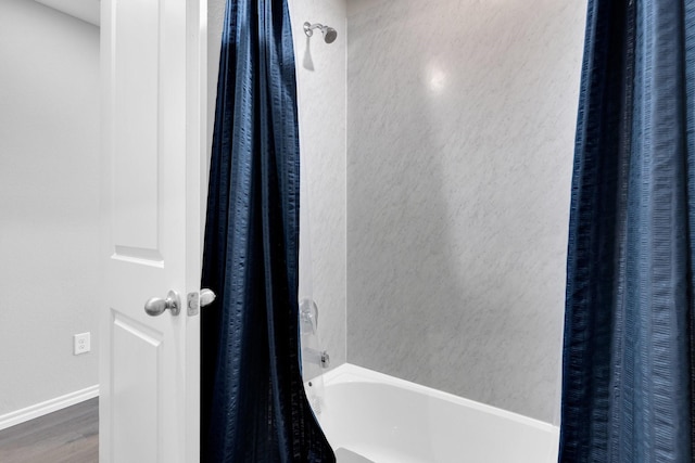 full bath with shower / tub combo, wood finished floors, and baseboards