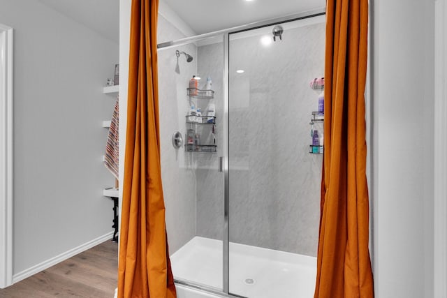 bathroom with wood finished floors and a shower stall