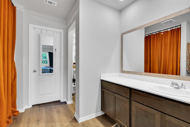 bathroom featuring vanity, visible vents, wood finished floors, and baseboards
