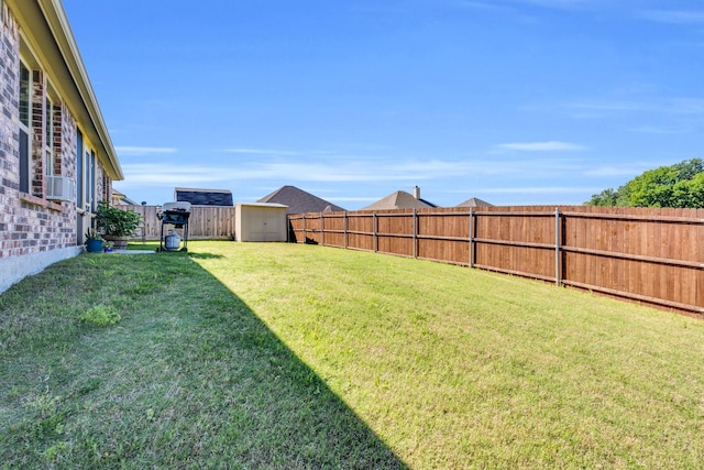 view of yard with a fenced backyard, a storage shed, and an outbuilding
