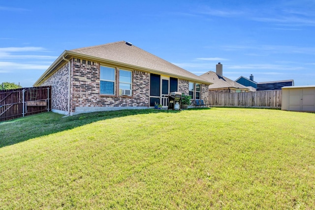rear view of property with a yard, brick siding, and a fenced backyard