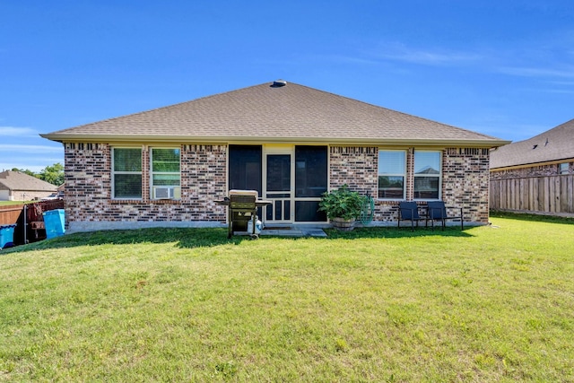 rear view of house with a lawn, brick siding, a shingled roof, and a fenced backyard