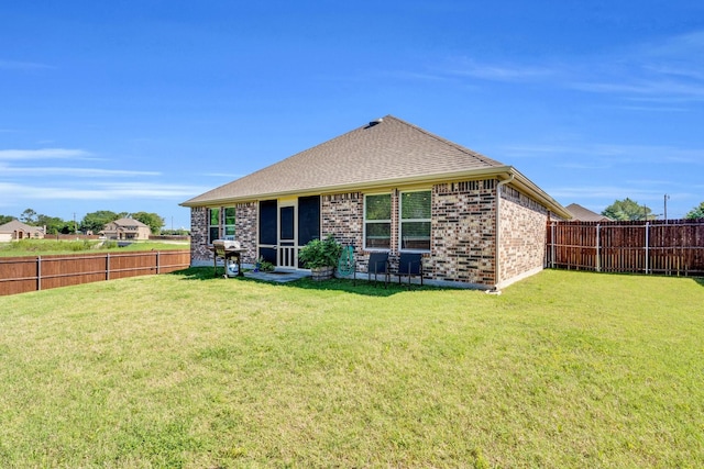back of property featuring a fenced backyard, a shingled roof, and a yard