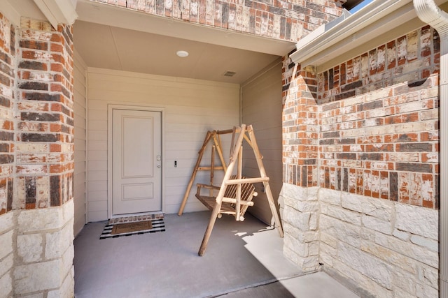 entrance to property featuring brick siding and visible vents