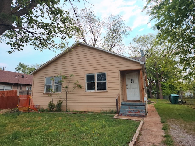 bungalow-style home with a front lawn and fence