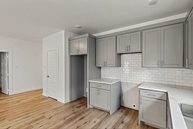 503 W Martin Luther King St, Denison, TX 75020 - kitchen featuring decorative backsplash, light wood-type flooring, and gray cabinets