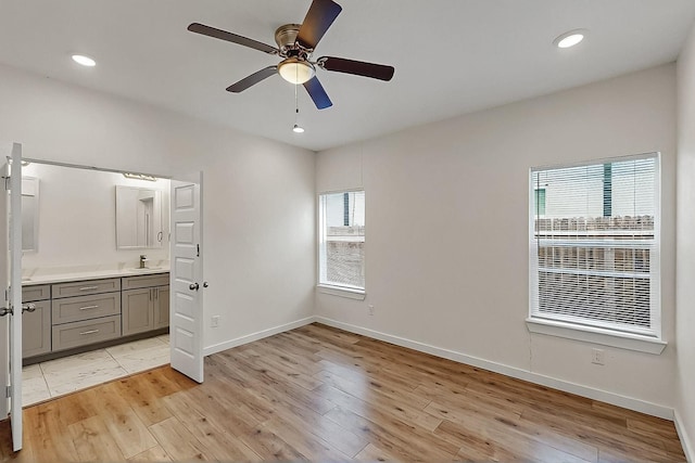 503 W Martin Luther King St, Denison, TX 75020 - unfurnished bedroom featuring connected bathroom, light wood-style floors, baseboards, and a sink