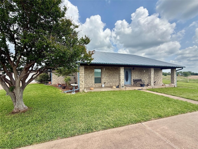 view of front of property with stone siding, a patio area, metal roof, and a front lawn