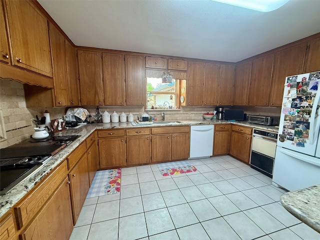 kitchen with brown cabinets, white appliances, a sink, and decorative backsplash