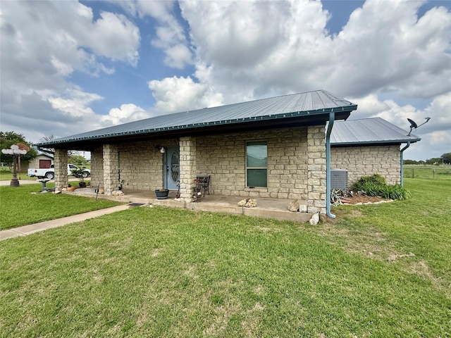 back of house with stone siding, a yard, metal roof, and a patio area