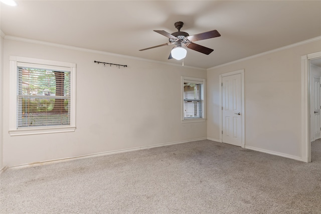 carpeted spare room featuring crown molding, baseboards, and ceiling fan