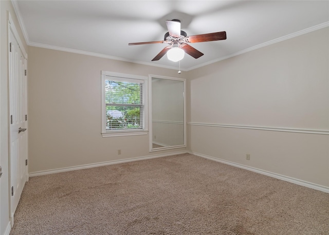 spare room featuring a ceiling fan, ornamental molding, carpet floors, and baseboards