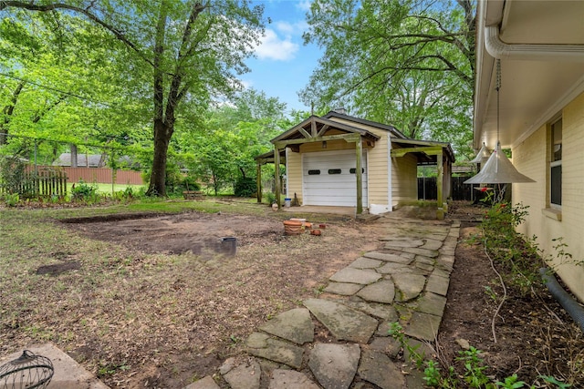 view of yard with an outbuilding, driveway, fence, and a garage