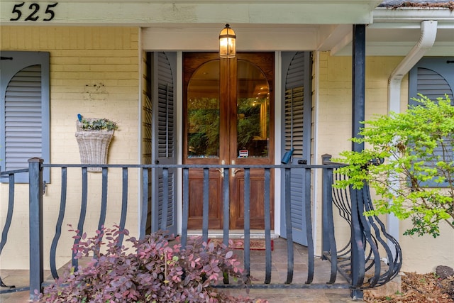 entrance to property with covered porch and brick siding