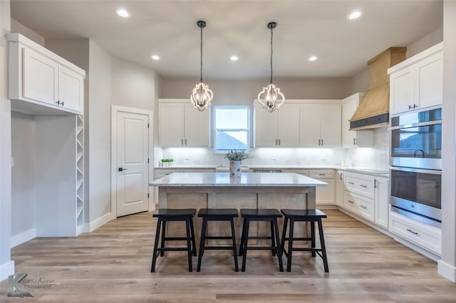 3342 Torrey Pne, Abilene, TX 79606 - kitchen with stainless steel double oven, a breakfast bar area, light wood finished floors, white cabinets, and a kitchen island