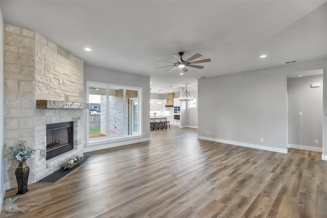 3342 Torrey Pne, Abilene, TX 79606 - unfurnished living room with ceiling fan with notable chandelier, a stone fireplace, visible vents, and wood finished floors