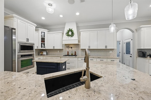 kitchen with backsplash, custom exhaust hood, white cabinets, and appliances with stainless steel finishes