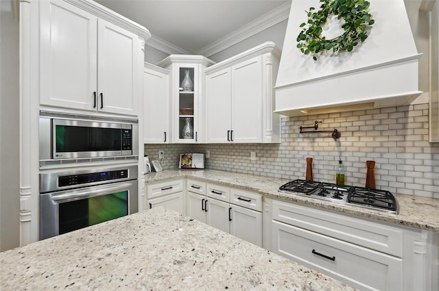 kitchen featuring glass insert cabinets, premium range hood, crown molding, stainless steel appliances, and white cabinets