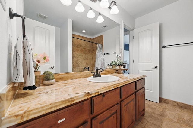 bathroom featuring vanity, visible vents, baseboards, and a tile shower