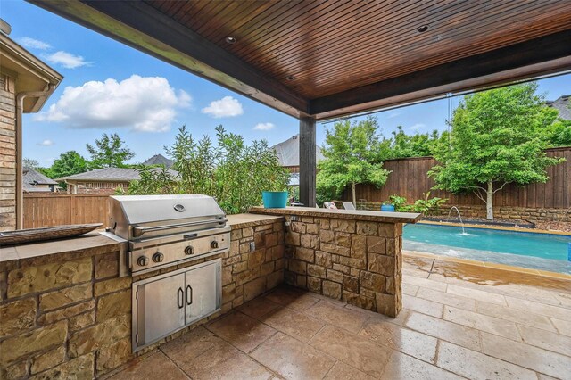 view of patio featuring a fenced backyard, exterior kitchen, a grill, and a fenced in pool