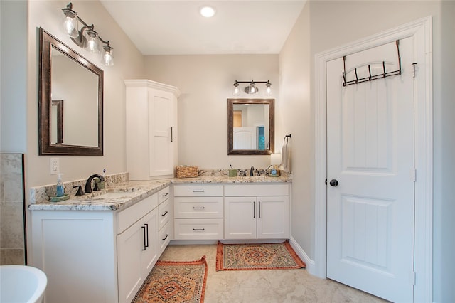bathroom with a soaking tub, double vanity, and a sink