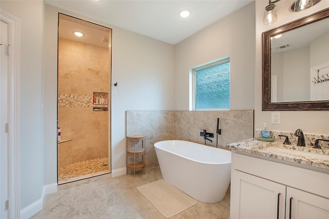 bathroom with tile walls, walk in shower, visible vents, vanity, and a freestanding bath