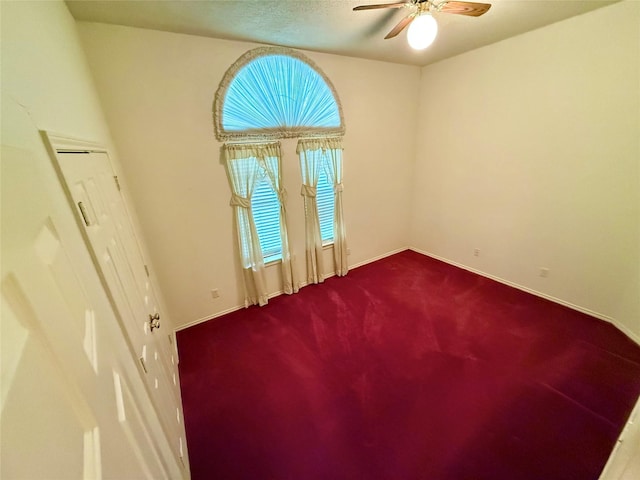 carpeted empty room featuring baseboards and ceiling fan