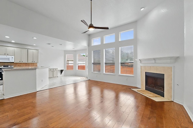 3405 Longneedle Ln, Mckinney, TX 75070 - unfurnished living room with light wood finished floors, a tiled fireplace, ceiling fan, and recessed lighting