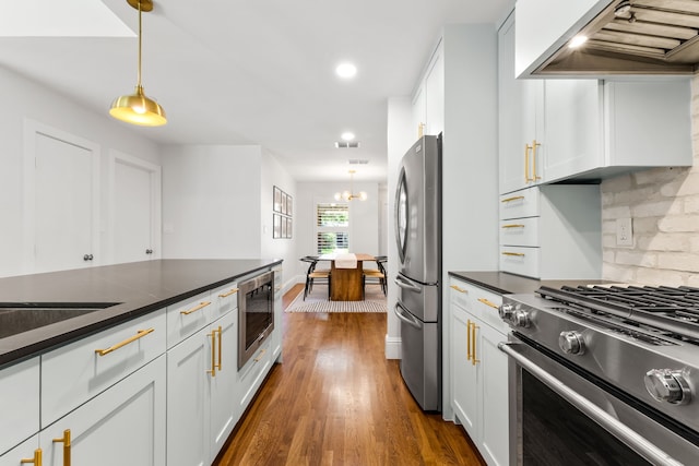 8831 Lanarkshire Dr, Dallas, TX 75238 - kitchen with wall chimney exhaust hood, stainless steel appliances, dark countertops, dark wood finished floors, and decorative light fixtures
