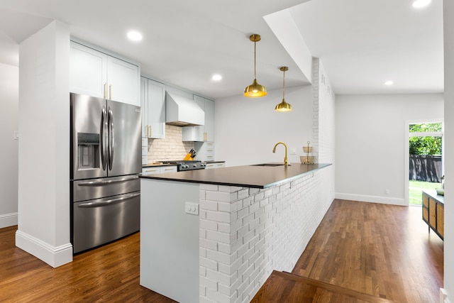 8831 Lanarkshire Dr, Dallas, TX 75238 - kitchen with stainless steel fridge, wall chimney range hood, a sink, dark countertops, and a peninsula