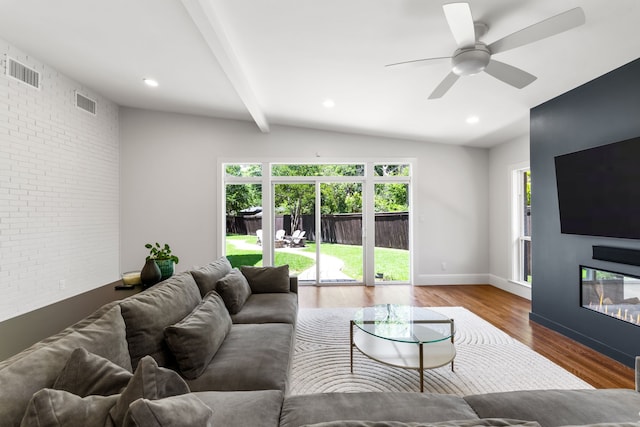 8831 Lanarkshire Dr, Dallas, TX 75238 - living room featuring brick wall, healthy amount of natural light, wood finished floors, ceiling fan, and a glass covered fireplace