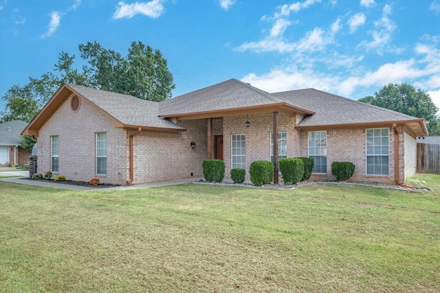 ranch-style house with a front yard, brick siding, roof with shingles, and fence