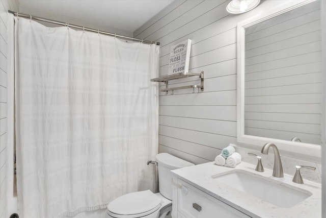 bathroom with toilet, wooden walls, vanity, and curtained shower