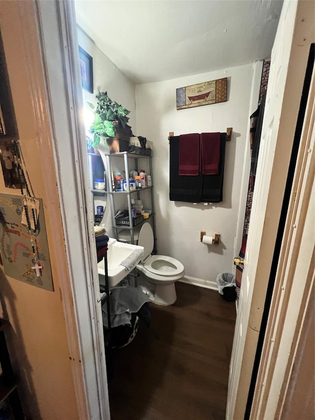 half bathroom featuring toilet, baseboards, and wood finished floors