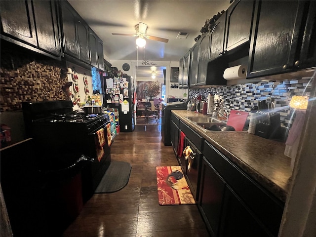 kitchen featuring a sink, tasteful backsplash, black gas range oven, freestanding refrigerator, and ceiling fan