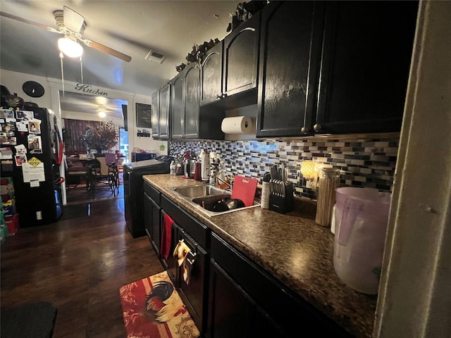 kitchen with dark cabinets, a ceiling fan, a sink, freestanding refrigerator, and tasteful backsplash