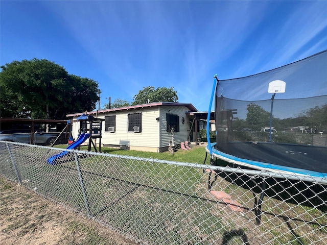 view of property exterior with a lawn, a trampoline, a playground, and fence