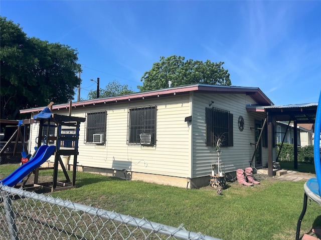 exterior space featuring a yard, cooling unit, a playground, and fence