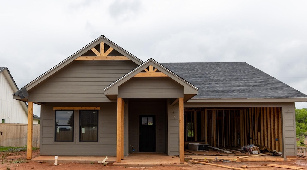 view of front facade with roof with shingles, fence, and an attached garage