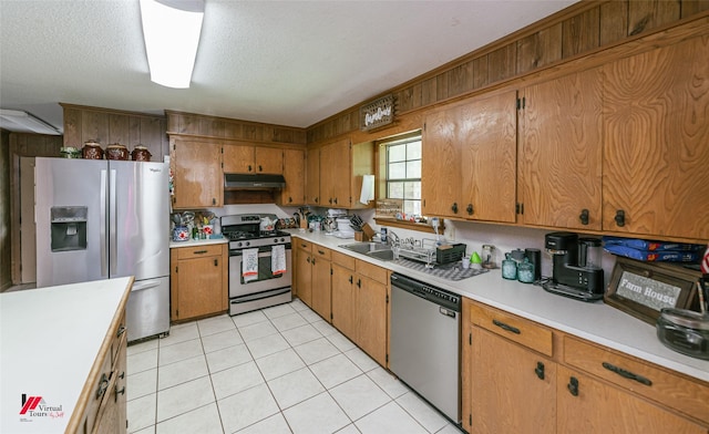 171 Columbia Road 84, Magnolia, AR 71753 - kitchen with stainless steel appliances, under cabinet range hood, light countertops, a sink, and brown cabinets