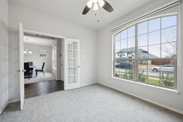 unfurnished room with ceiling fan with notable chandelier, carpet floors, french doors, and a healthy amount of sunlight