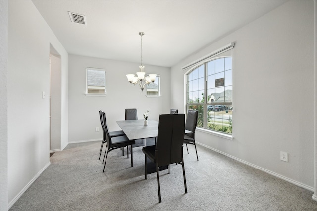 carpeted dining space with baseboards, a healthy amount of sunlight, an inviting chandelier, and visible vents