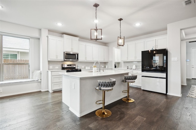 kitchen with visible vents, a sink, white cabinetry, appliances with stainless steel finishes, and dark wood-style floors