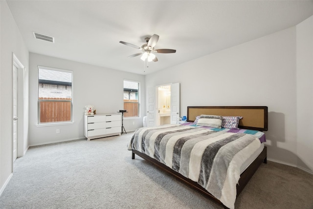 carpeted bedroom featuring baseboards, ceiling fan, ensuite bath, and visible vents